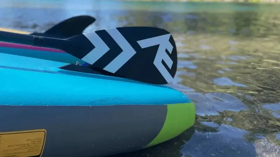 Inflatable paddle board with fin and paddle on lake - perfect holiday gift for water sports enthusiasts