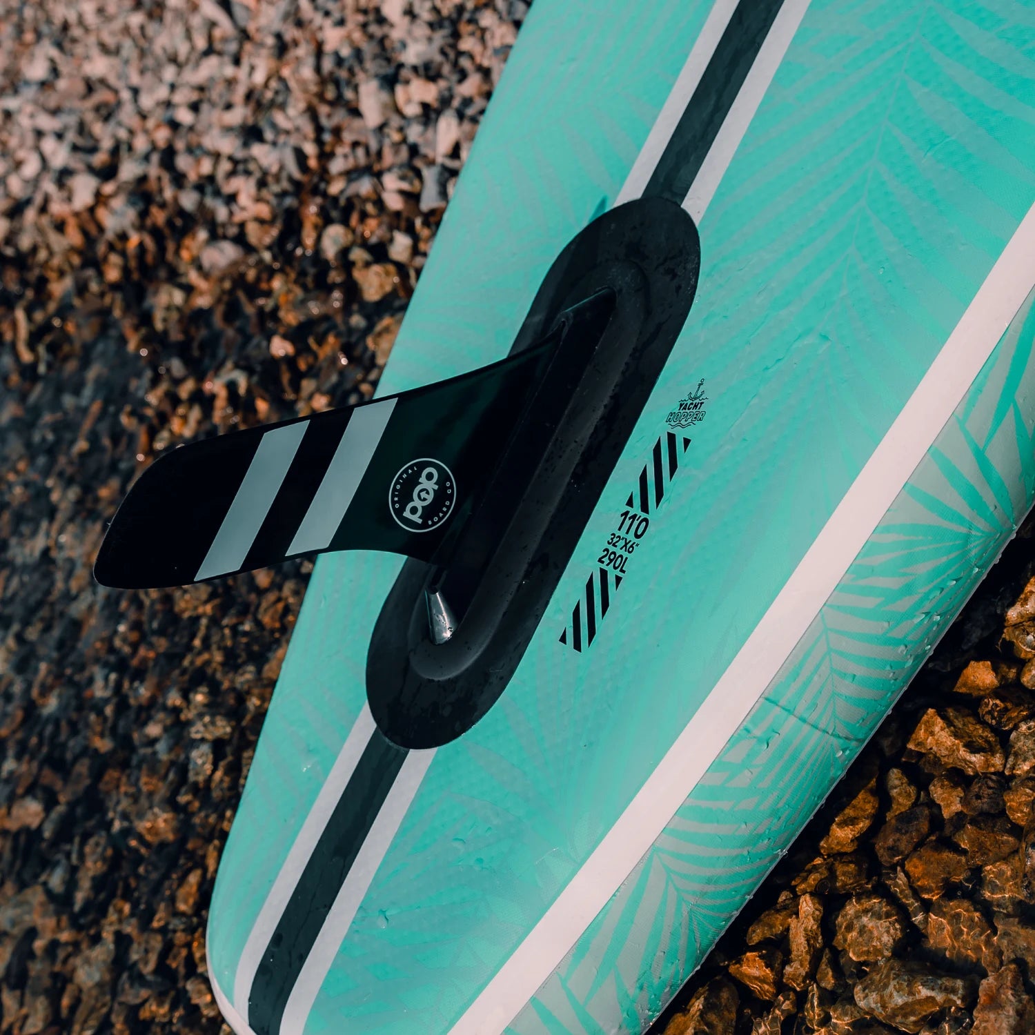 POP Yacht Hopper paddleboard with black striped fin system and teal leaf print design.