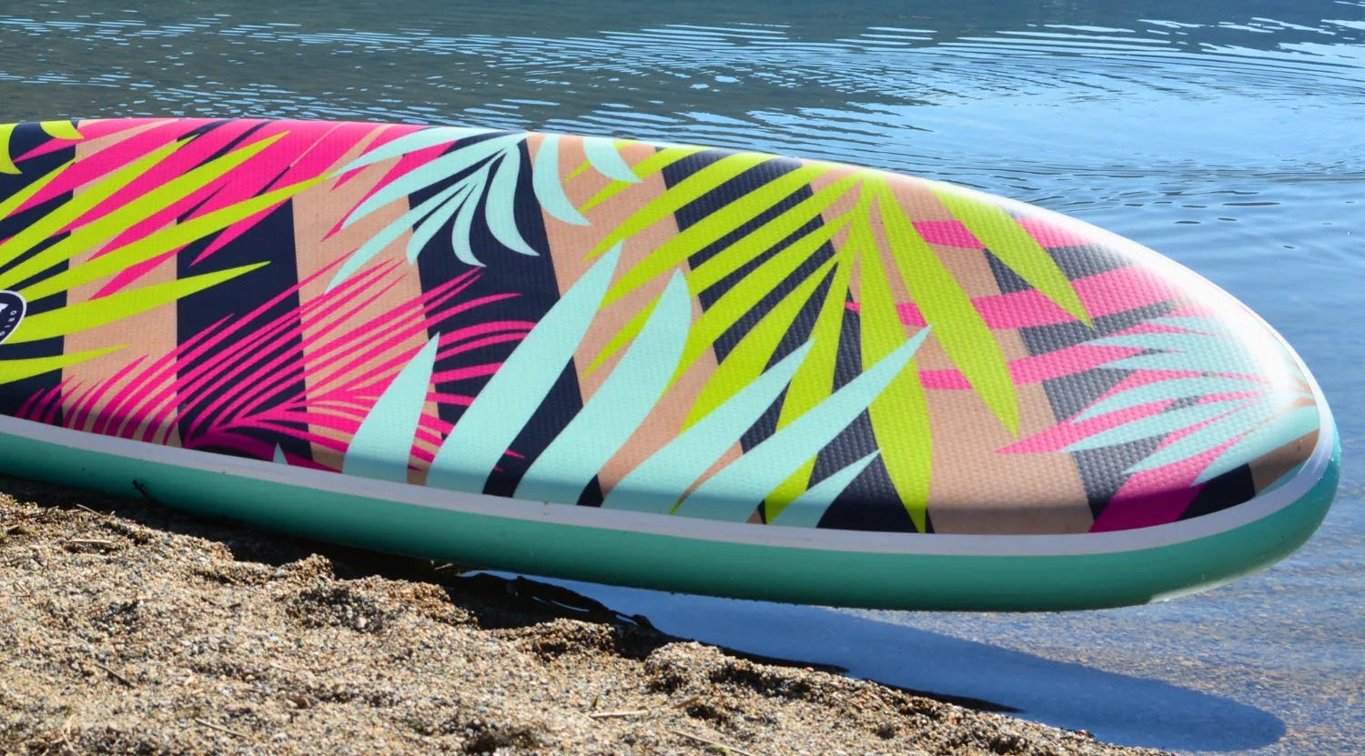 POP Royal Hawaiian 10’6 inflatable paddleboard resting at an angle on sandy lakeside beach.