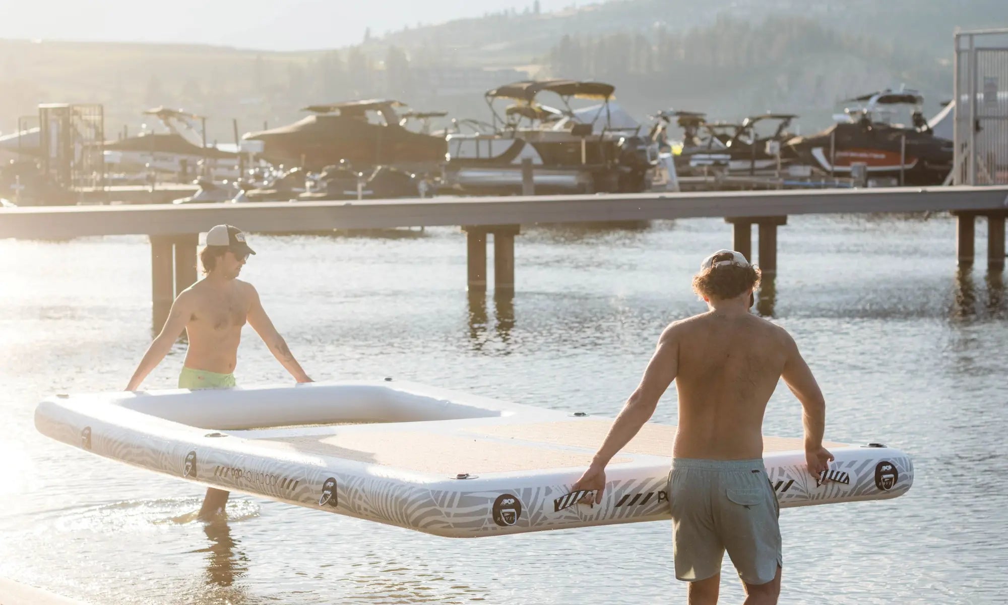 Two people carrying POP AquaDock 14x7 inflatable dock into the lake in Canada.
