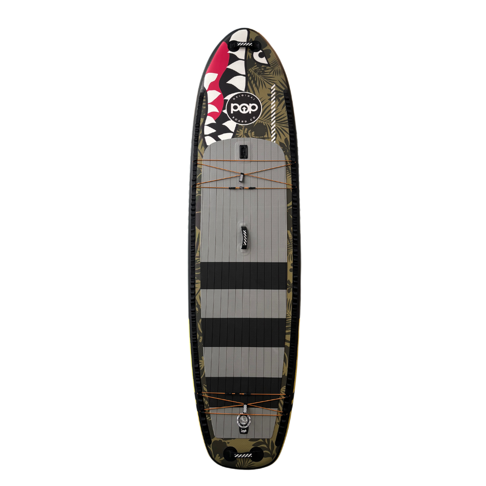 Top view of the 11'6" El Capitan Bomber inflatable paddleboard, featuring the signature shark mouth nose graphic, green camo print, and grey non-slip deck pad with black stripes.